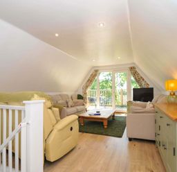 A living room with sofas a coffee table and a television near balcony doors at 60 Valley Lodge in Callington near Gunnislake