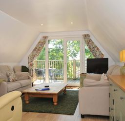 A living room with sofas a coffee table a television and sliding doors leading to a balcony at 60 Valley Lodge in Callington near Gunnislake