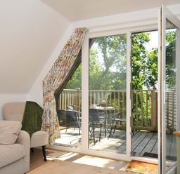 A living room with glass doors opening to a balcony with table and chairs at 60 Valley Lodge Callington near Gunnislake