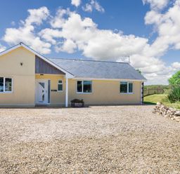 A single-story house with a gravel driveway and small garden at Cae Berllan in Mynytho near Pwllheli