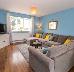 A living room with a sofa and television at Cae Berllan in Mynytho near Pwllheli
