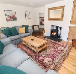 A living room with gray sofas green and yellow cushions wooden coffee table and a fireplace at Widgeons Keel in Flushing