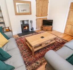 A living room with two sofas a wooden coffee table a rug a fireplace a television and a bookshelf at Widgeons Keel in Flushing