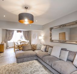 A living room with a large gray sectional sofa and a dining area with wooden chairs at Family House in Weymouth