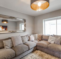 A living room with a large gray sectional sofa and a mirror above it at Family House in Weymouth