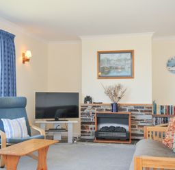 A living room with a television and bookshelf at Zapadiah in Polzeath