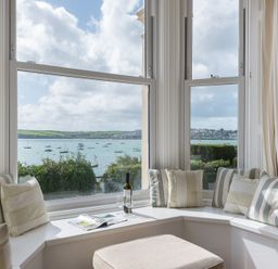 A window seat with cushions overlooking a bay with boats at 4 The Terrace in Rock