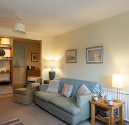 A living room with armchair couch side table lamps and bookshelf at Pencreek Rock