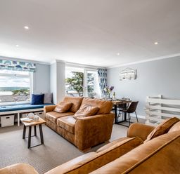 A living room with brown sofas a window seat and a dining table at Slipway 15 in Rock