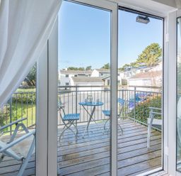 A balcony with a small blue table and two blue chairs viewed through glass doors at Slipway 19 in Rock