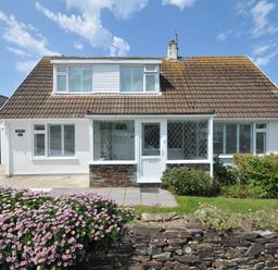 A house with a flower bed and garage at Sunset in Polzeath
