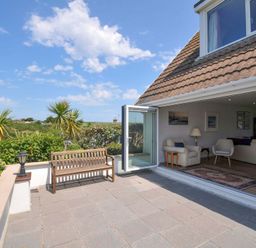 An outdoor terrace with bench and sliding door at Sunset in Polzeath