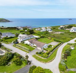 A coastal residential area with houses grassy lawns and roads near the sea at Trebartha in Daymer Bay