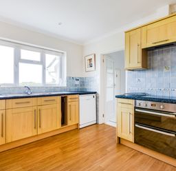 A kitchen with wooden cabinets a dishwasher an oven and a window at Trebartha in Daymer Bay