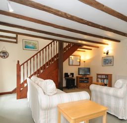 A living room with striped sofas a wooden staircase and a TV at The Granary in Rock