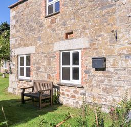 An exterior view of a stone building with a bench at The Granary Rock