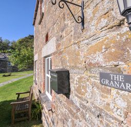 Exterior view of The Granary with a stone wall and bench at The Granary in Rock