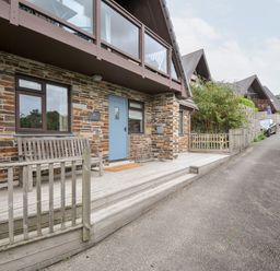 An outdoor view of a house with a blue door and a wooden bench at Rocklings in Rock