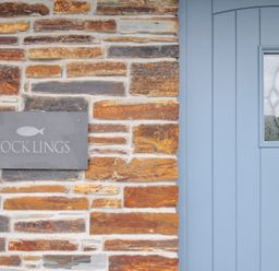 A stone wall with a blue door and a nameplate at Rocklings in Rock