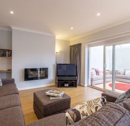 A living room with brown sofas and a television next to glass sliding doors at Cogenhoe in Rock