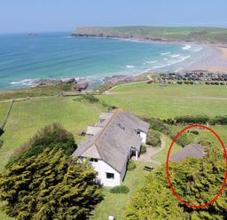 A coastal house with a grey roof near a beach with parked cars and waves at Gullsway September Tide in Polzeath