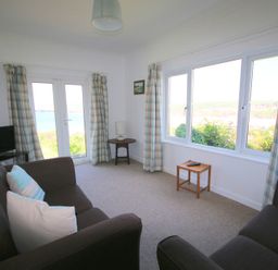 A sitting room with two brown sofas a small wooden table and a television at Gullsway September Tide in Polzeath