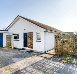 A white bungalow with a blue door and garage with trellis fencing in front at Little Sailing in Rock