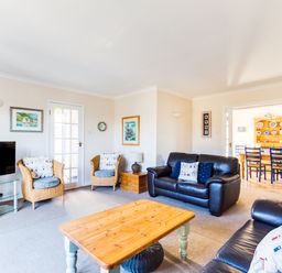 A living room with leather sofas wicker chairs a wooden coffee table and a television at Little Sailing in Rock