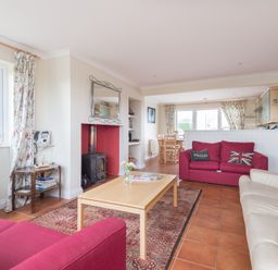 A living room with two red sofas a beige sofa and a wooden coffee table at Kirra in Polzeath
