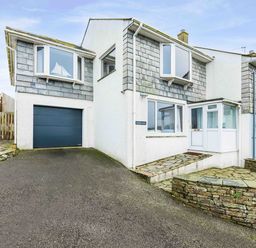 The exterior of a two-story house with a garage driveway and stone patio at Shilling Stones in Port Isaac