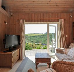 A living room with a television and sofa at Cartway Cabin in Port Isaac