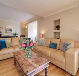 A living room with leather sofas a wooden coffee table with flowers and table lamps at Worthy House Daymer Bay