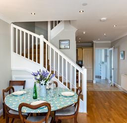 A dining area with a round table set near stairs and a bookshelf in a hallway at Lowenna Manor 4 Rock