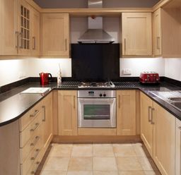 A kitchen with wooden cabinets black countertops stainless steel oven and appliances at Lowenna Manor 4 Rock