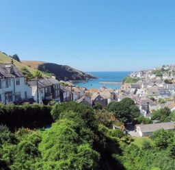 A coastal village with houses on a hillside overlooking the ocean and boats in the water at April Cottage in Port Isaac