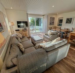 A living room with gray sofas a television on a wooden cabinet and a dining table with chairs at Carn Du 1 in Rock