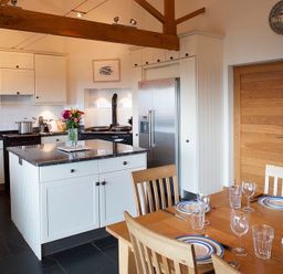 A kitchen with a dining table set with plates glasses and cutlery at Ossco in Polzeath