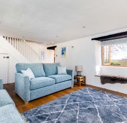 A living room with blue sofas a gray rug and a window seat at Dingles Cottage in Rock