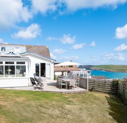 A house with a patio and outdoor dining furniture overlooking the sea at Atlantis in Polzeath