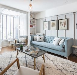 A living room with a light blue sofa three framed pictures on the wall and a coffee table with cups and a plant at Albany in Port Isaac