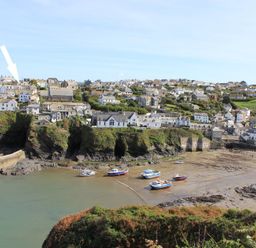 A coastal village with boats on the shore and houses on cliffs at Albany in Port Isaac