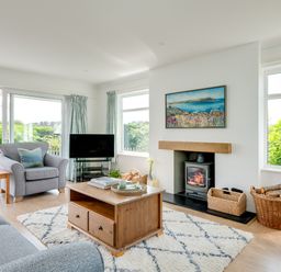A living room with grey sofas a wooden coffee table and a fireplace with baskets at Tremay in Rock