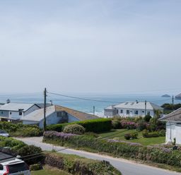 A coastal residential area with houses gardens and a view of the sea at The Point in Polzeath