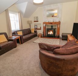 A living room with brown leather sofas a rug and a fireplace at Cheviot Hills in Wooler
