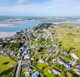 An aerial view of a coastal village with houses roads green fields and water at Rock Hill in Rock