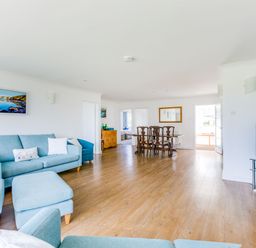 A living room with blue sofas and armchairs wooden dining table and chairs a flat screen television and wooden floor at Rock Hill in Rock
