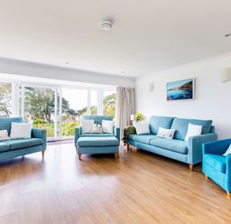 A living room with three blue sofas a large window and wooden flooring at Rock Hill in Rock