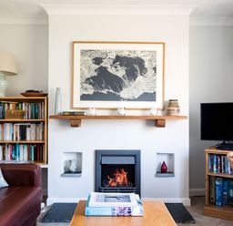 A living room with a fireplace a bookshelf a TV and a coffee table with books at Bella Vista in Polzeath