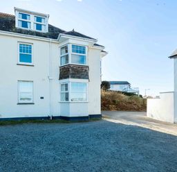 Exterior view of a white two-story building with several windows and a gravel driveway at Pinewood Flat 5 in Polzeath
