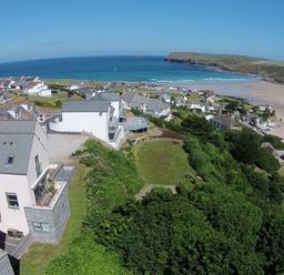 A coastal village with houses near a beach and a headland with the sea in the background at Kellan in Polzeath